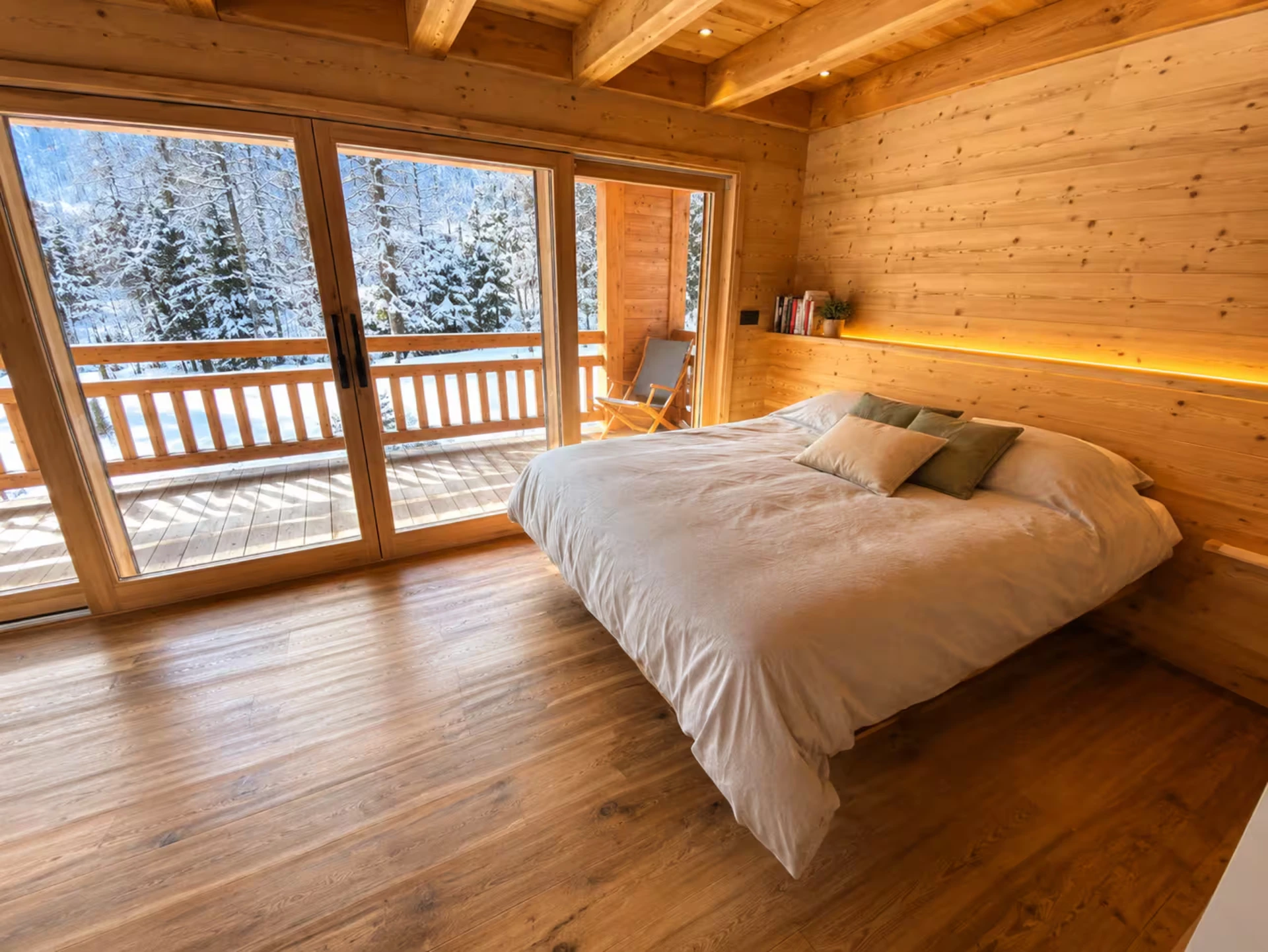 Camera da letto con pareti in legno e vista sul balcone innevato